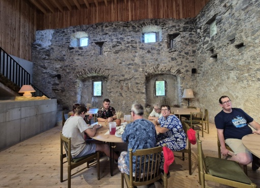 Eine Gruppe von Menschen sitz an runden Tischen in einer Burg.