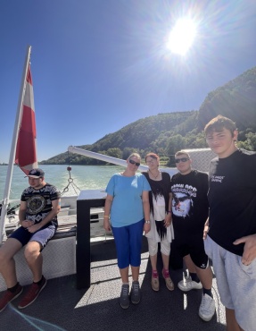 F&uuml;nf Personen stehen am Deck eines Schiffes und l&auml;cheln in die Kamera.