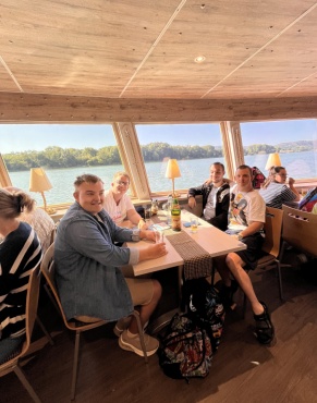Eine Frau und 3 M&auml;nner sitzen an einem Tisch und l&auml;cheln in die Kamera.