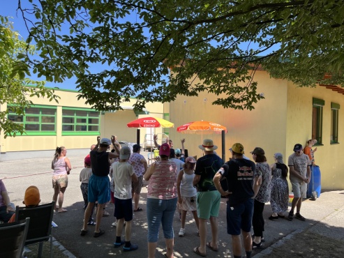 Eine Gruppe von Menschen steht im Garten und hört sich ein Konzert an.
