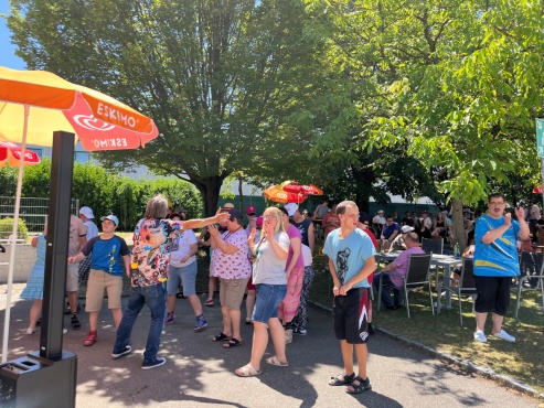 Ein Mann singt im Garten vor einer tanzenden Gruppe von Menschen.