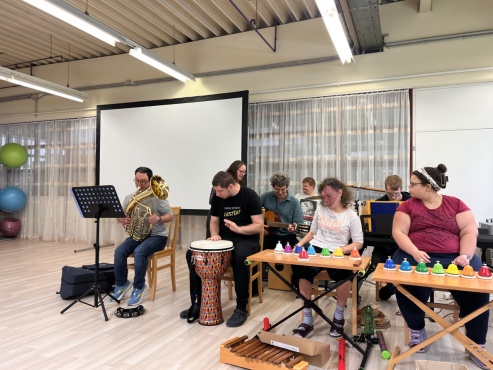 Eine Gruppe von Menschen musiziert mit verschiedenen Instrumenten.
