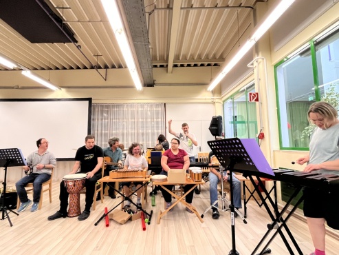 Eine Gruppe von Menschen musiziert mit verschiedenen Instrumenten.