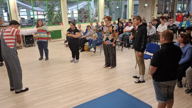 6 Personen stehen in Halbkreis vor einem Clown.