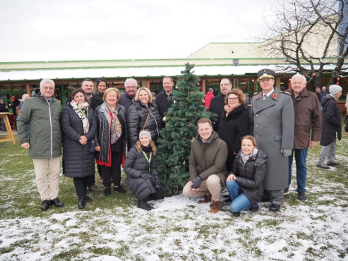 Ein Gruppe von Menschen steht versammelt im Garten und l&auml;chelt in die Kamera.