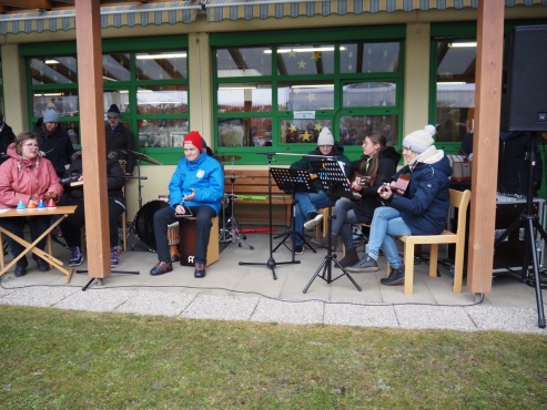 Eine Gruppe von Menschen musiziert auf verschiedenen Instrumenten.