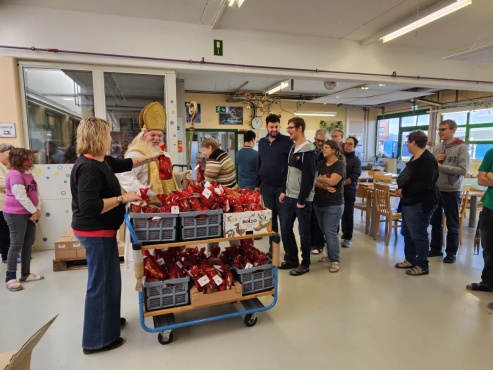 Eine Gruppe von Menschen steht in der Reihe und bekommt Geschenke vom Nikolaus.