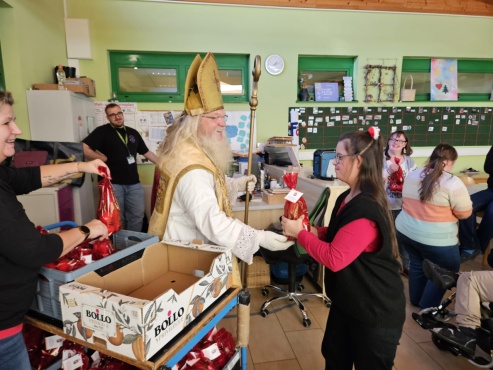 Der Nikolaus überreicht ein Geschenk an eine Frau.