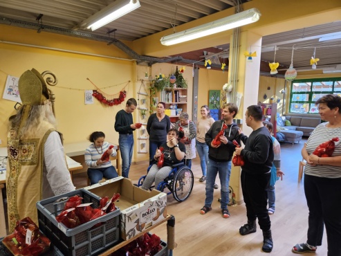 10 Personen stehen vor dem Nikolaus und halten ihre Geschenke.