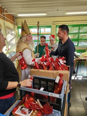 Der Nikolaus überreicht einem Mann ein Geschenk.