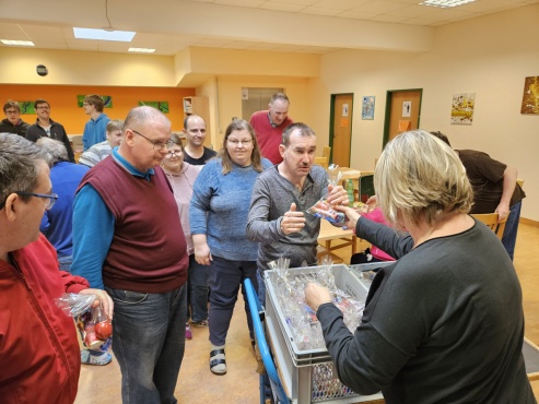 Eine Gruppe von Menschen steht in der Reihe und bekommt Geschenke von einer Frau überreicht