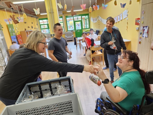 Eine Frau überreicht ein Geschenk an eine im Rollstuhl sitzende Frau.