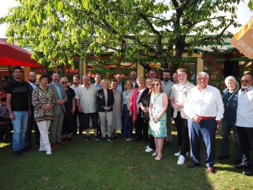 Ein Gruppe von Menschen posiert im Garten und lächelt in die Kamera.