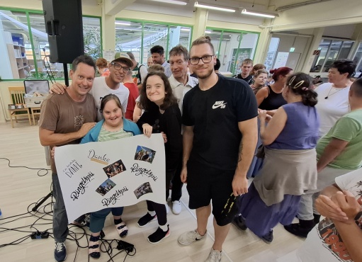 6 Personen lächeln in die Kamera. Sie halten ein großes Plakat in den Händen.
