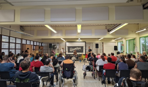 Eine Gruppe von Menschen sitzt auf Stühlen und verfolgt eine Musikaufführung.