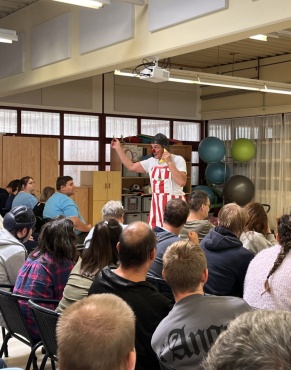 Ein Clown f&uuml;hrt eine Show auf vor einem sitzenden Publikum.