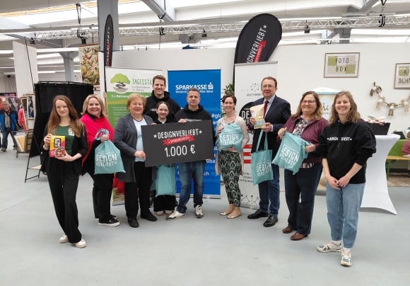 Eine Gruppe von Menschen l&auml;chelt in die Kamera. Sie halten einen &uuml;bergro&szlig;en Scheck.