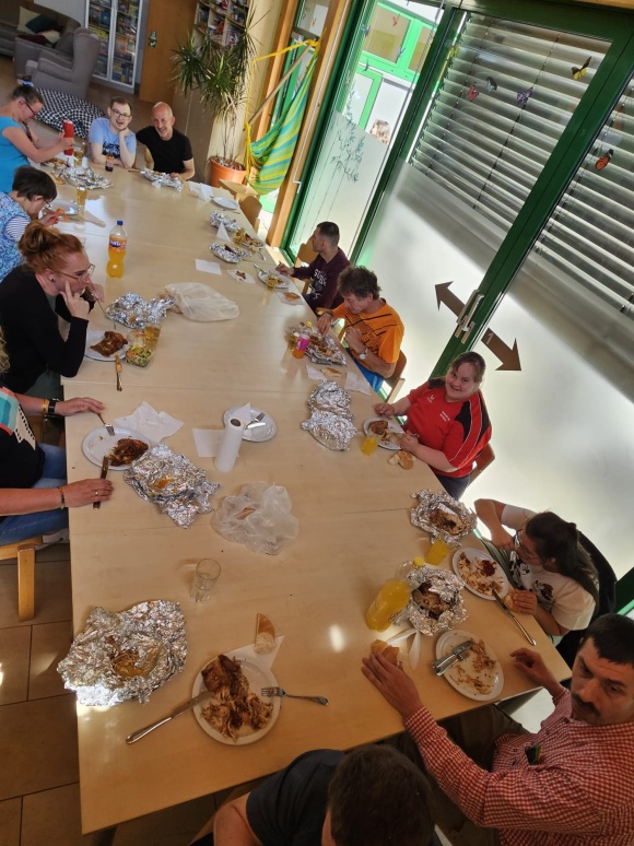 Eine Gruppe von Menschen sitzt an einem langen Tisch und isst.